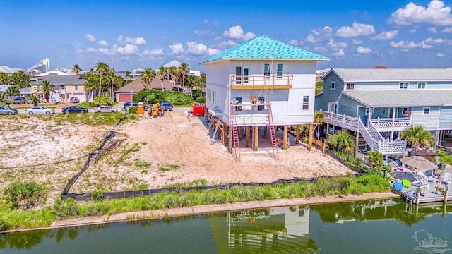 back of property with a residential view, a water view, and a balcony