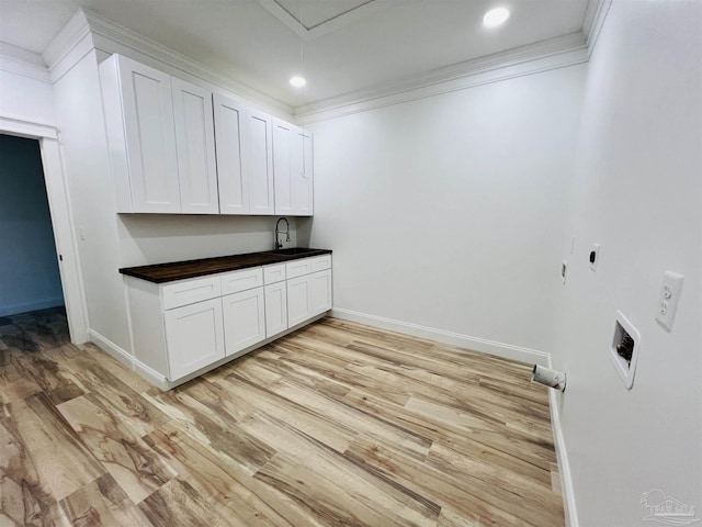 laundry area with crown molding, light wood-style flooring, cabinet space, and a sink