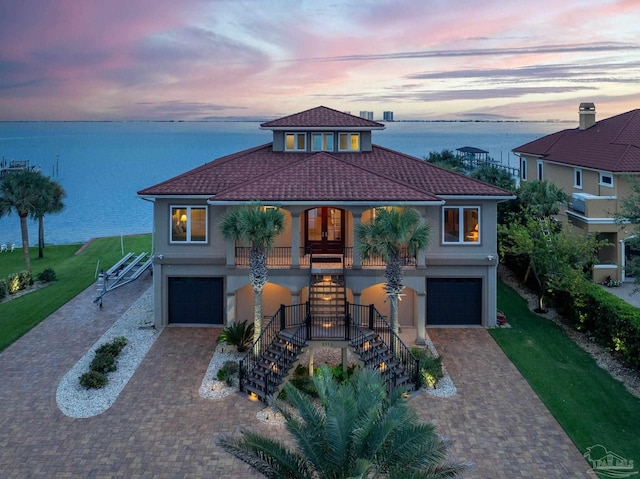 view of front facade with covered porch, a water view, and a garage