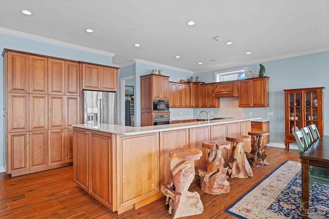 kitchen featuring a large island, light wood-type flooring, ornamental molding, and appliances with stainless steel finishes