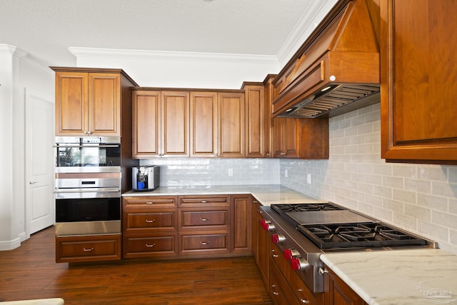 kitchen featuring appliances with stainless steel finishes, brown cabinetry, and custom exhaust hood