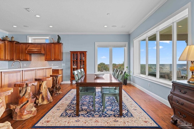 dining room with crown molding, sink, light hardwood / wood-style floors, and a textured ceiling