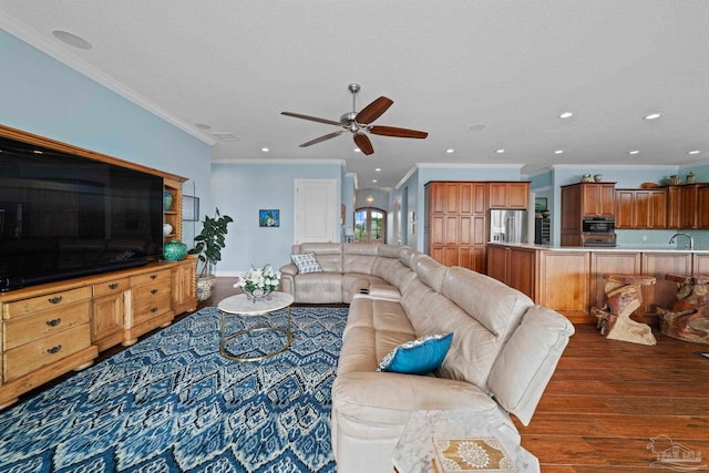 living room featuring ornamental molding, a textured ceiling, ceiling fan, sink, and dark hardwood / wood-style floors