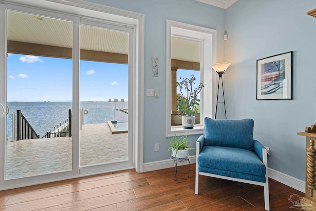 sitting room with hardwood / wood-style floors, a water view, and crown molding