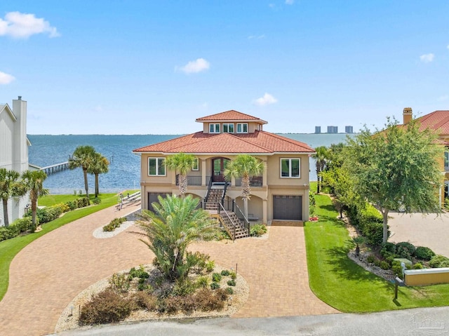 mediterranean / spanish house featuring a porch, a garage, a water view, and a front yard