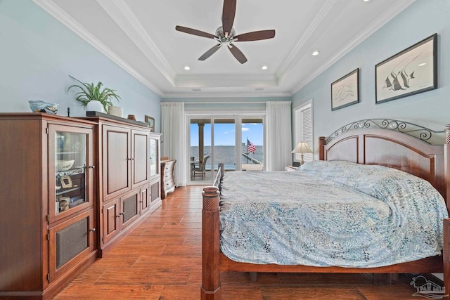 bedroom featuring hardwood / wood-style floors, a raised ceiling, ceiling fan, access to exterior, and ornamental molding