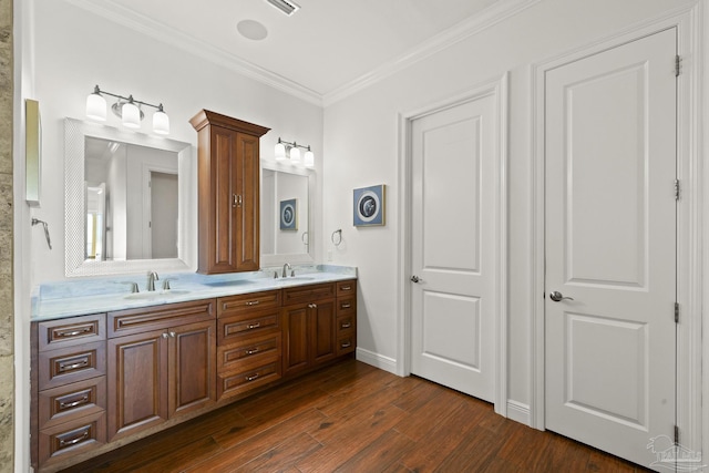 full bathroom featuring double vanity, crown molding, a sink, and wood finished floors