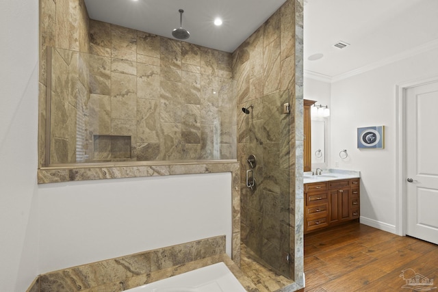 full bathroom with a stall shower, baseboards, wood finished floors, crown molding, and vanity