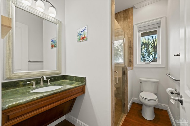 full bath featuring a stall shower, baseboards, toilet, wood finished floors, and a sink