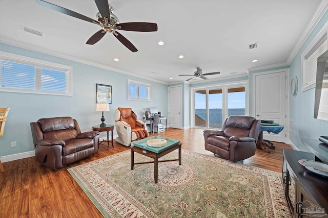 living room with crown molding, a water view, and hardwood / wood-style flooring