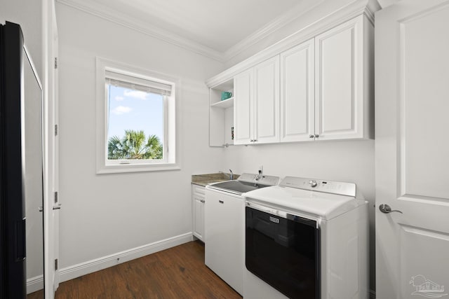 laundry area featuring dark wood-style floors, washing machine and clothes dryer, cabinet space, ornamental molding, and baseboards