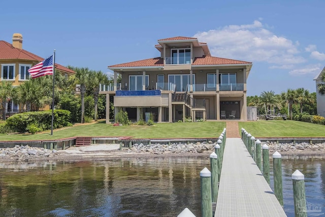 back of house featuring a lawn, a water view, a balcony, and stucco siding