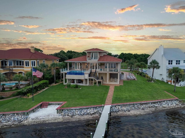 back house at dusk with a yard and a water view