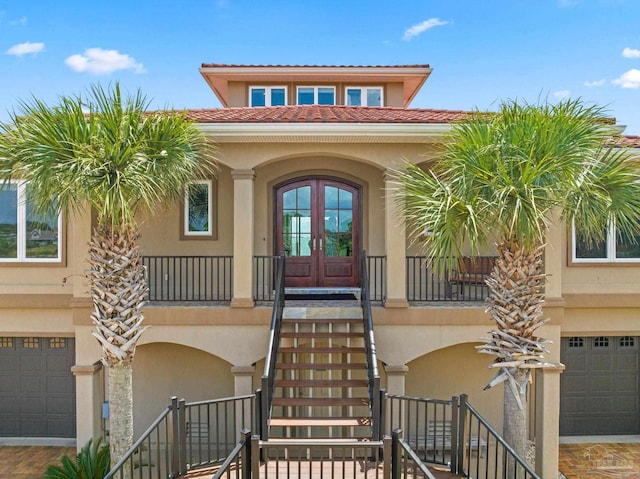 doorway to property with a garage, french doors, and stucco siding