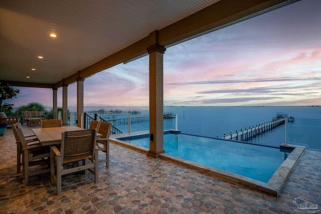 patio terrace at dusk with a water view and a boat dock