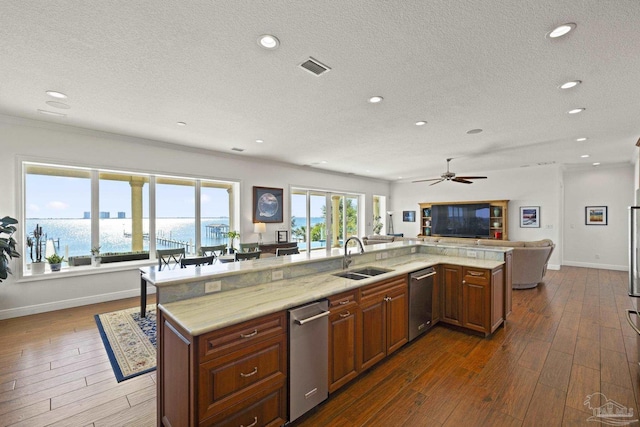 kitchen featuring a water view, dark wood-type flooring, open floor plan, a sink, and a large island with sink