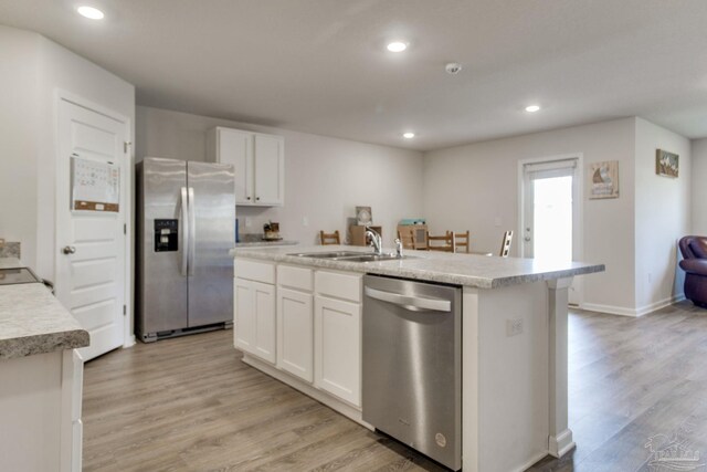 kitchen featuring an island with sink, white cabinetry, stainless steel appliances, and light countertops