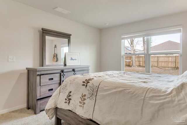 bedroom featuring baseboards, visible vents, and light colored carpet