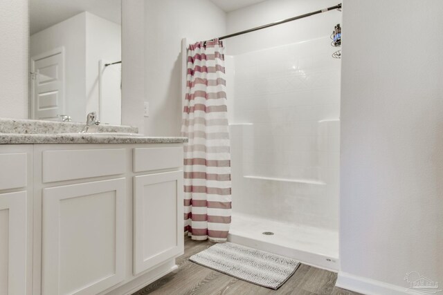 full bath with a shower stall, vanity, and wood finished floors