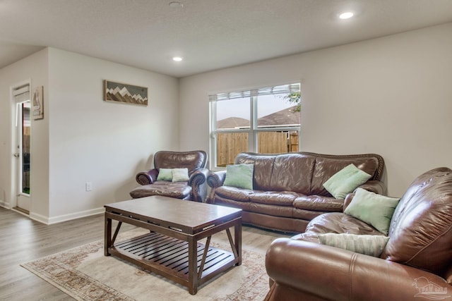 living area with baseboards, recessed lighting, and light wood-style floors