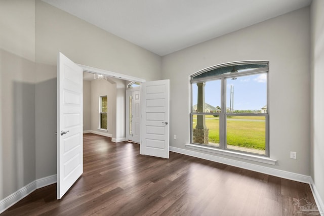 unfurnished room with baseboards and dark wood-style flooring