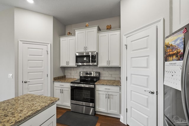 kitchen with white cabinets, light stone counters, backsplash, and appliances with stainless steel finishes