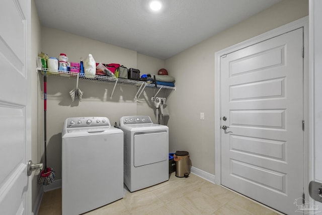 laundry area with washing machine and dryer, baseboards, and laundry area