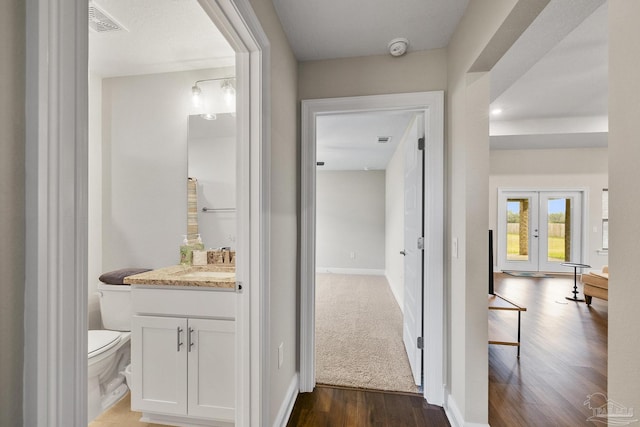 bathroom with baseboards, toilet, wood finished floors, vanity, and french doors