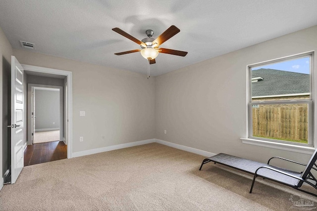 carpeted spare room featuring visible vents, a textured ceiling, baseboards, and ceiling fan
