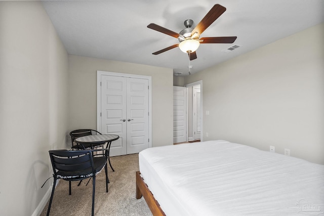 bedroom featuring a closet, visible vents, baseboards, a ceiling fan, and light colored carpet