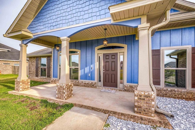 view of exterior entry with covered porch and board and batten siding