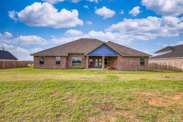 back of house featuring brick siding, fence, french doors, and a yard
