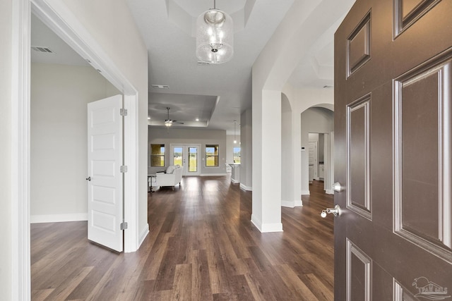 foyer with a ceiling fan, dark wood-style floors, baseboards, visible vents, and arched walkways