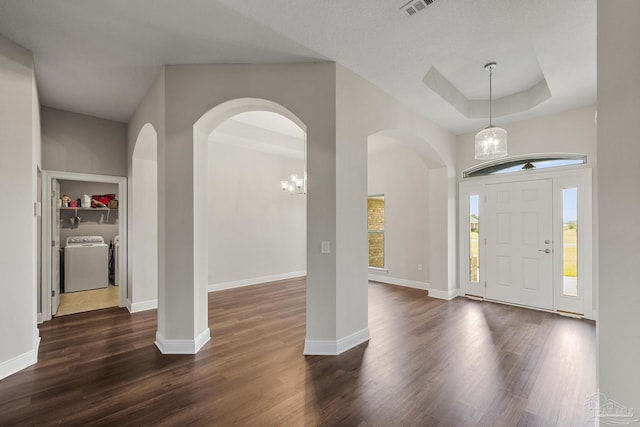 foyer featuring baseboards, washing machine and dryer, arched walkways, and dark wood-type flooring