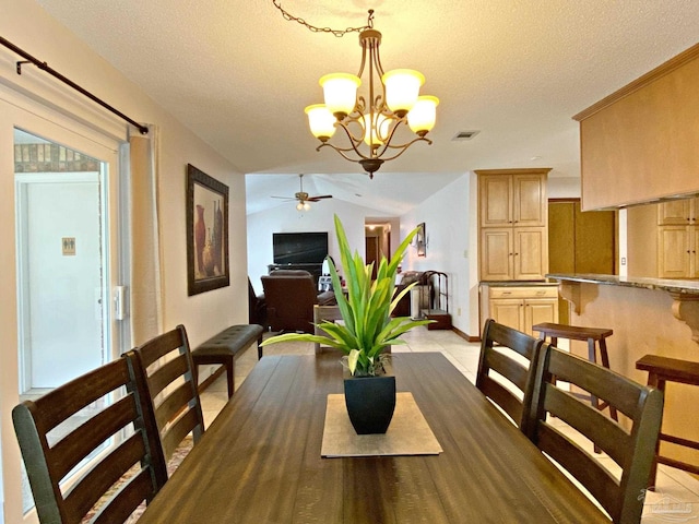 tiled dining area with lofted ceiling, ceiling fan with notable chandelier, and a textured ceiling