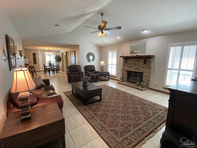 tiled living room featuring ceiling fan with notable chandelier, a fireplace, vaulted ceiling, and a textured ceiling