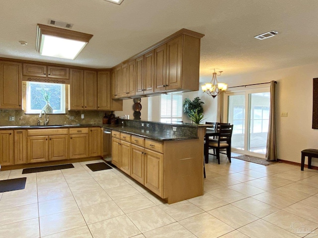 kitchen with an inviting chandelier, kitchen peninsula, sink, and light tile patterned floors