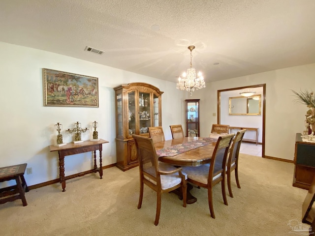 dining area with light colored carpet, a chandelier, and a textured ceiling