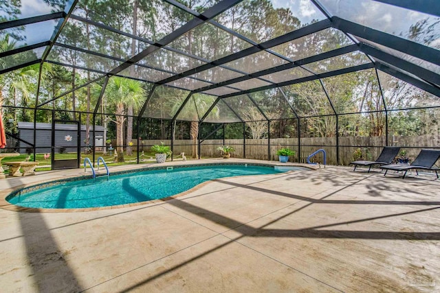 view of swimming pool with glass enclosure, a storage shed, and a patio area