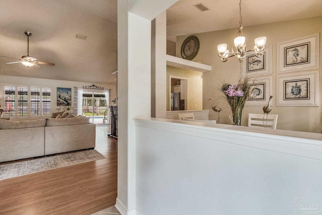 interior space featuring stainless steel fridge, hardwood / wood-style floors, ceiling fan with notable chandelier, and decorative light fixtures