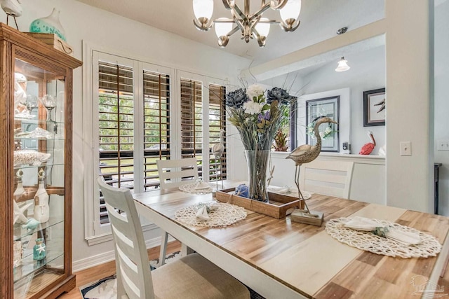 dining room with hardwood / wood-style flooring, a notable chandelier, and lofted ceiling