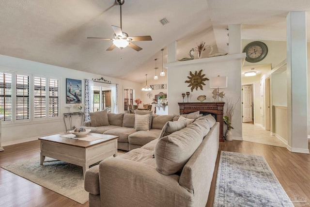 living room with ceiling fan with notable chandelier, wood-type flooring, and high vaulted ceiling