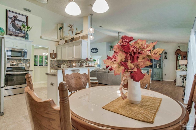 dining space with a textured ceiling, lofted ceiling, and light tile patterned flooring