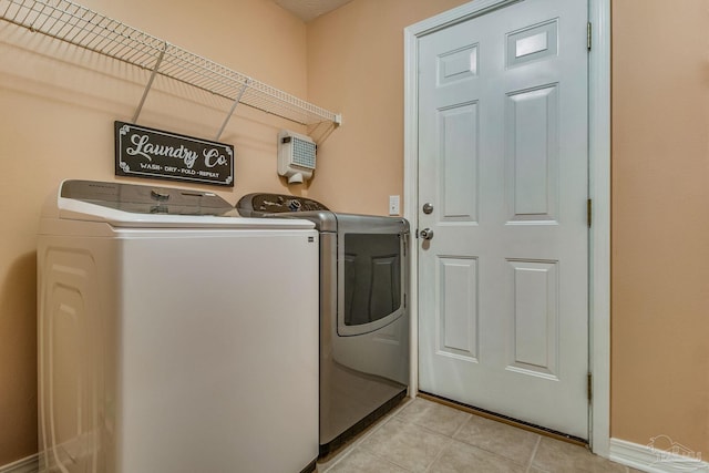 clothes washing area featuring washing machine and dryer and light tile patterned floors