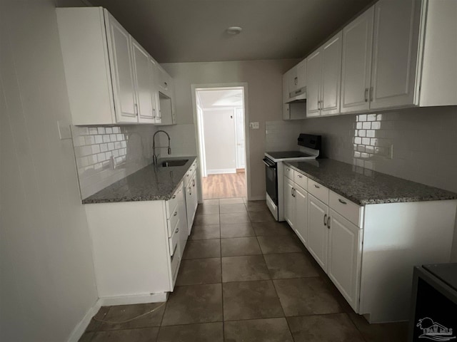 kitchen with dark stone countertops, white electric range, sink, and white cabinets