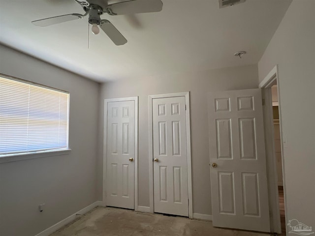 unfurnished bedroom featuring ceiling fan, two closets, and baseboards