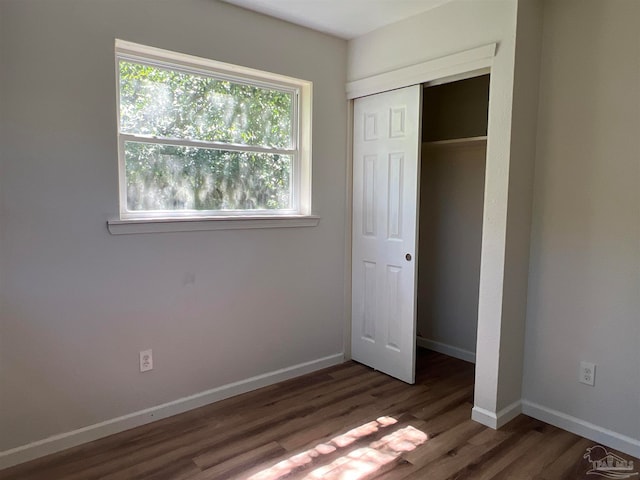 unfurnished bedroom featuring a closet, baseboards, and wood finished floors