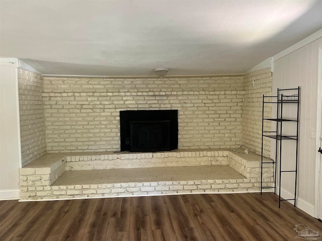 unfurnished living room featuring brick wall and dark hardwood / wood-style floors