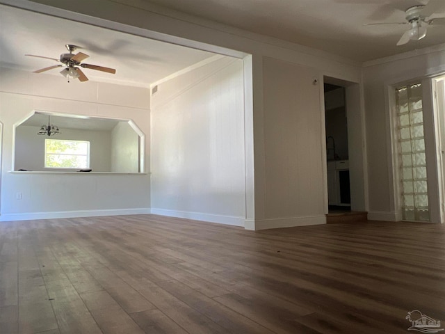 empty room with ornamental molding, ceiling fan with notable chandelier, and wood finished floors