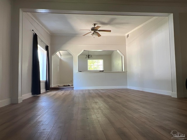 empty room with arched walkways, ceiling fan, baseboards, and wood finished floors